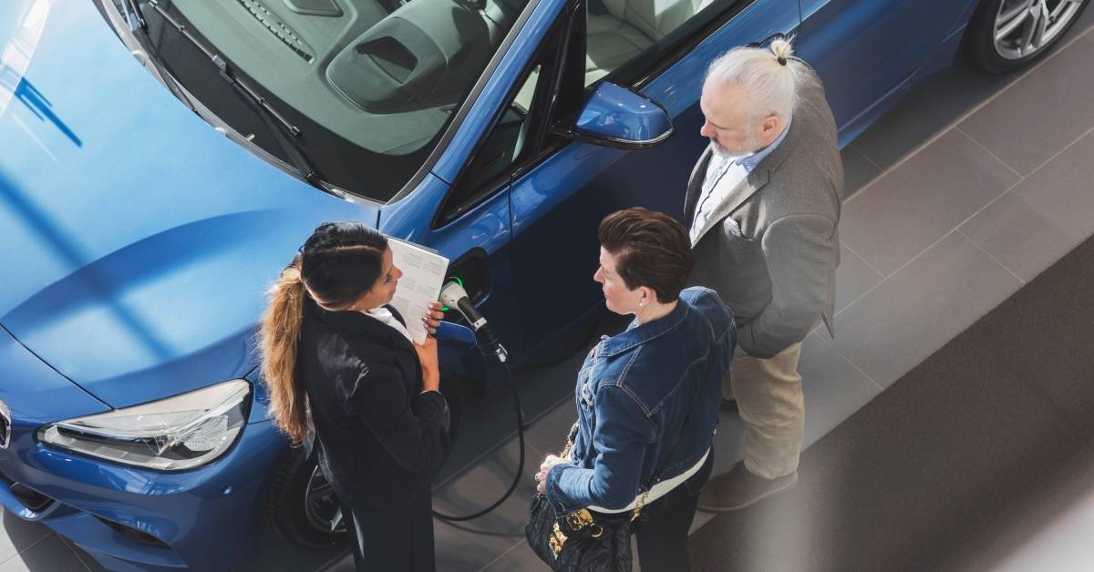 a-high-angle-view-is-seen-of-a-saleswoman-talking-to-customers-at-a-car-showroom--lead